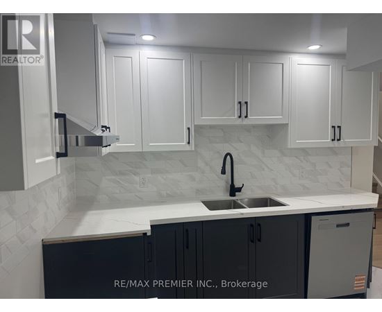 A kitchen with white cabinets and a marble backsplash.
