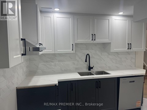 A kitchen with white cabinets and a marble backsplash.
