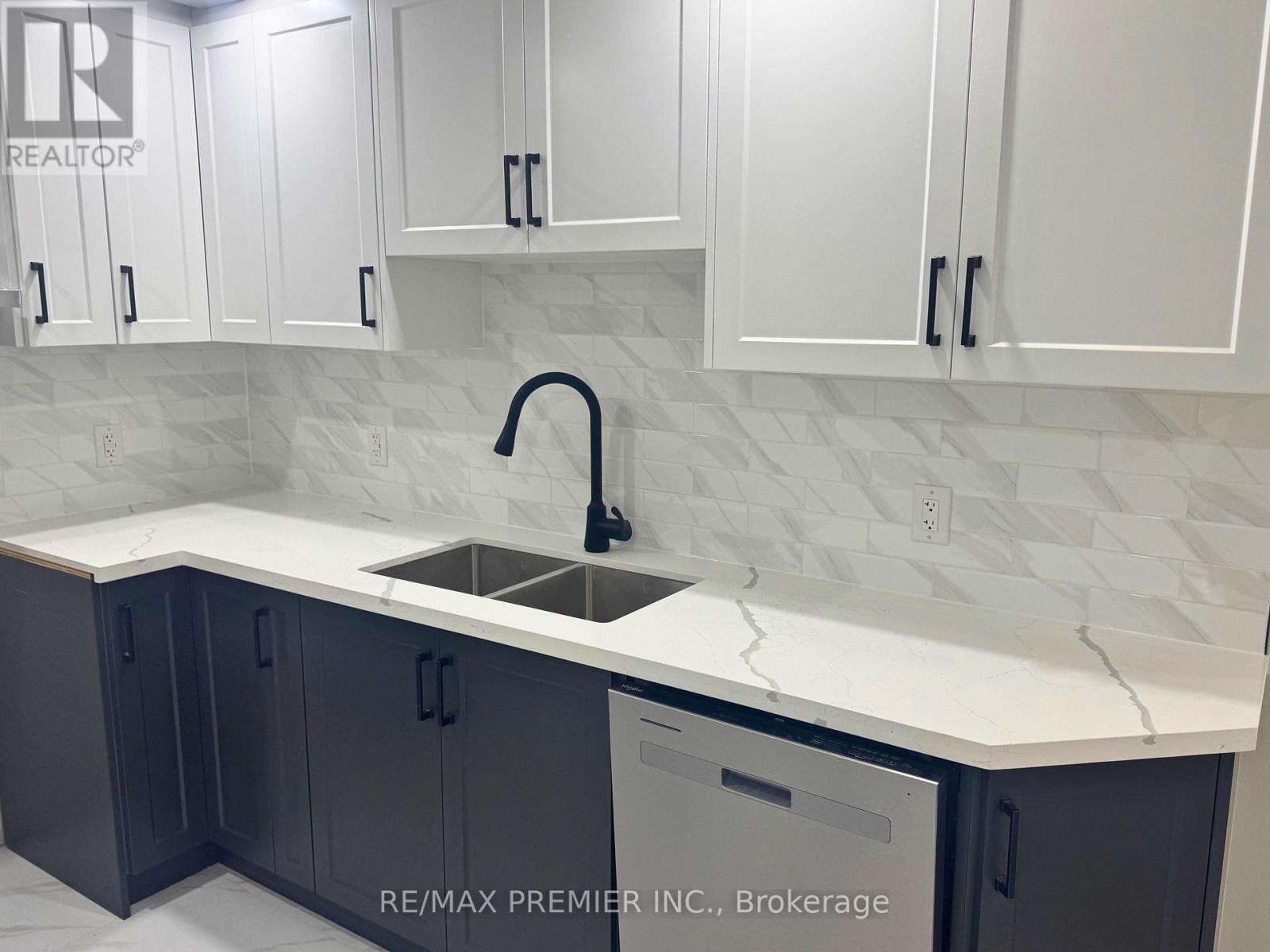 A kitchen with white cabinets and a marble countertop.