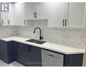 A kitchen with white cabinets and a marble countertop.