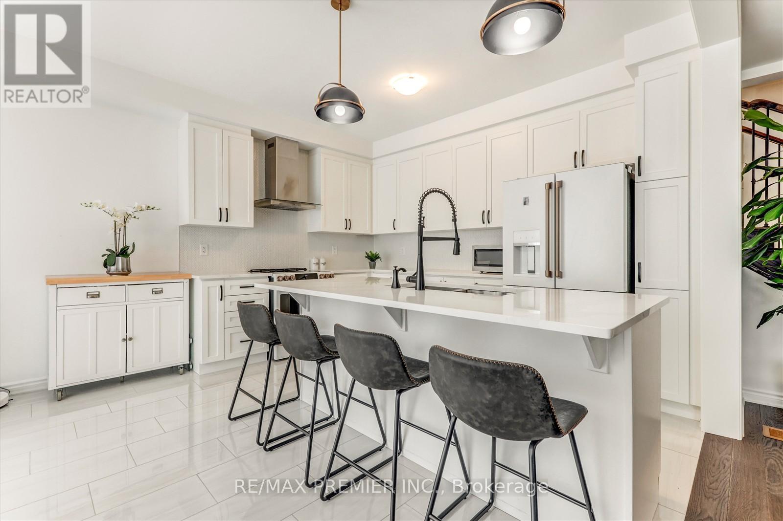 A kitchen with white cabinets and a white island with three barstools.