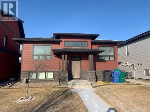 A red house with a brown roof and a grey garage door.