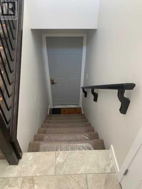 A stairway with a carpeted runner and a black handrail.