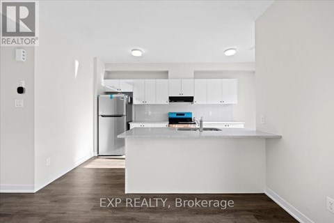 A kitchen with white cabinets and a countertop is shown in a real estate listing.