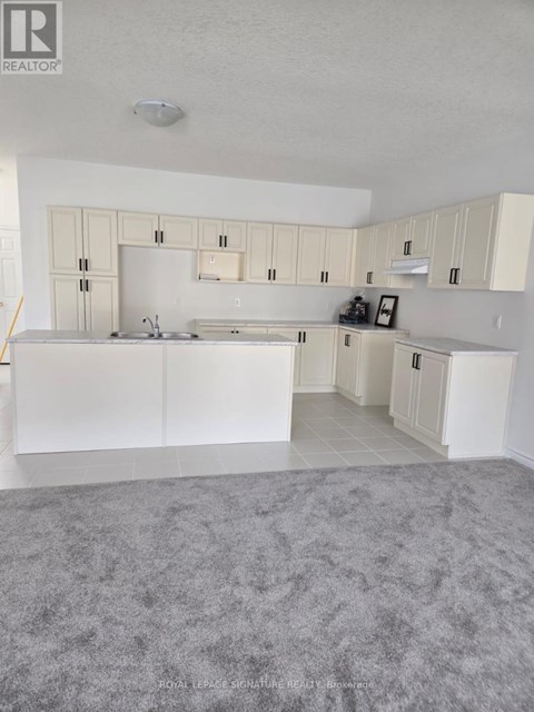 A realtor photo of a white kitchen with a grey carpet.
