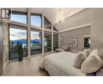 A bedroom with a large bed and a view of the mountains through the windows.