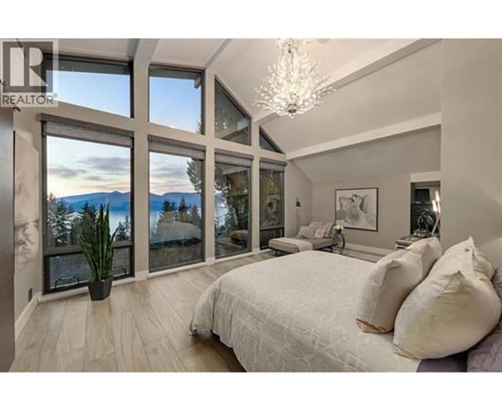 A bedroom with a large bed and a view of the mountains through the windows.
