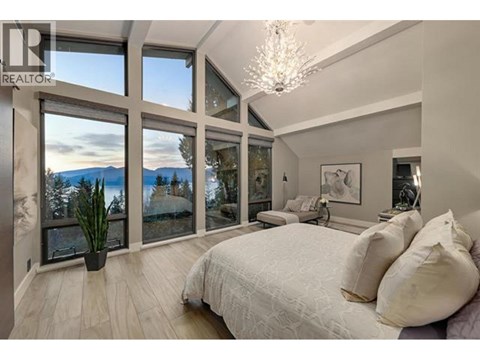 A bedroom with a large bed and a view of the mountains through the windows.