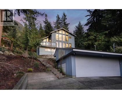 A house with a garage is surrounded by trees.