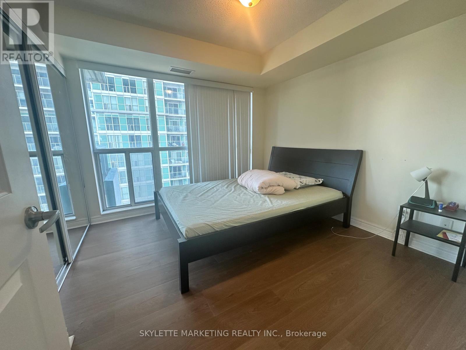 A bedroom with a large bed and a window overlooking a city.