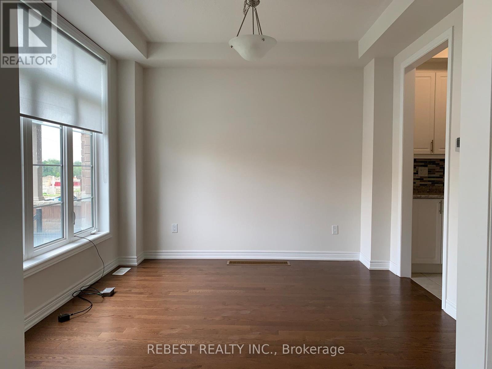 A room with wooden floors and white walls, with a window on the left side.