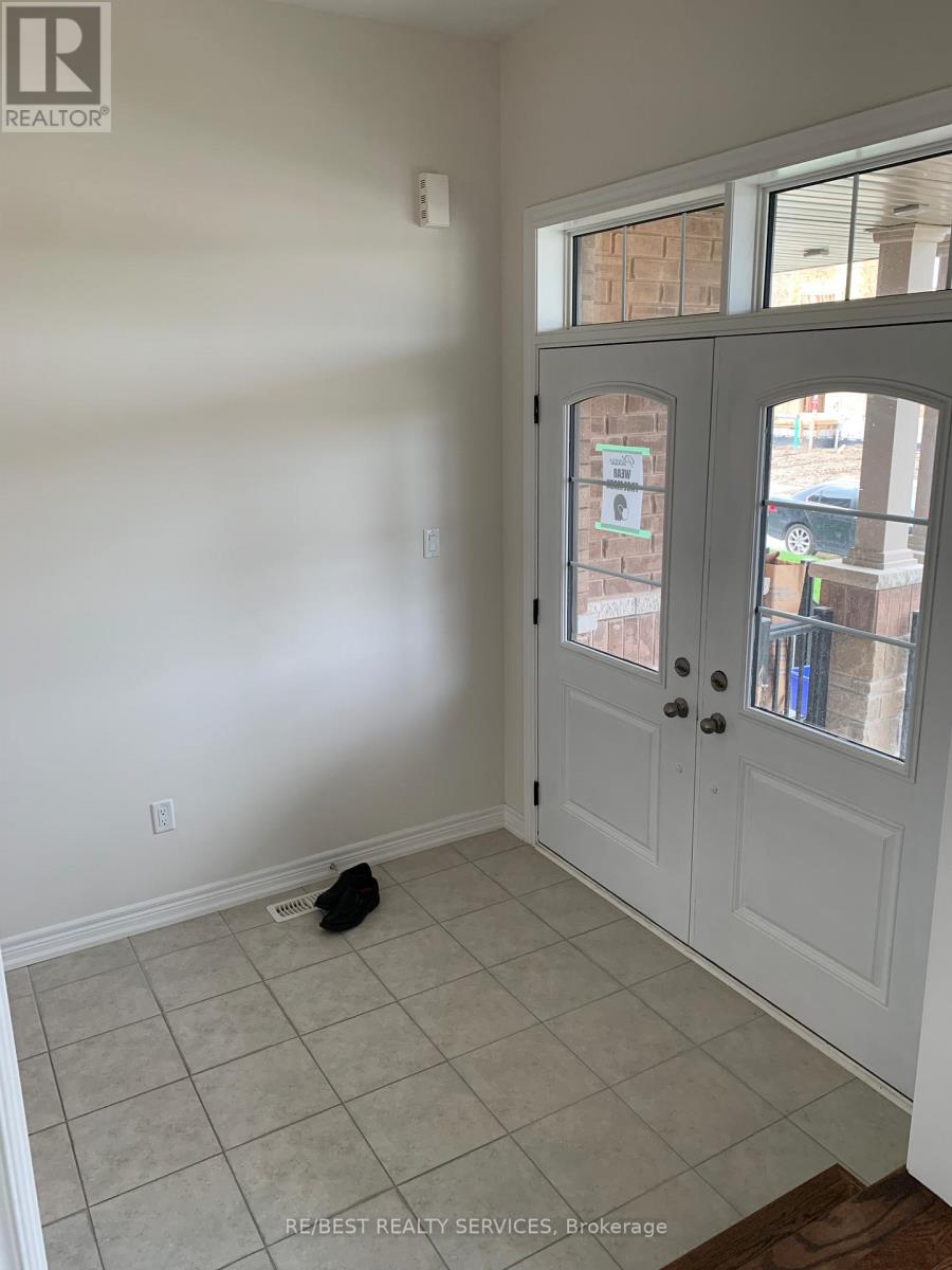 A black cat is sitting on a tiled floor in a room with a white door.