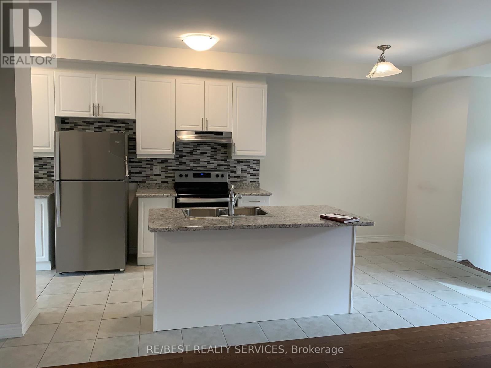 A kitchen with a refrigerator, sink, and cabinets.