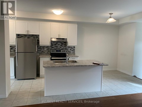A kitchen with a refrigerator, sink, and cabinets.