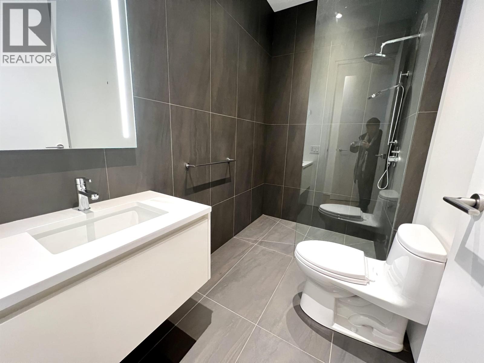 A modern bathroom with a white sink and toilet.