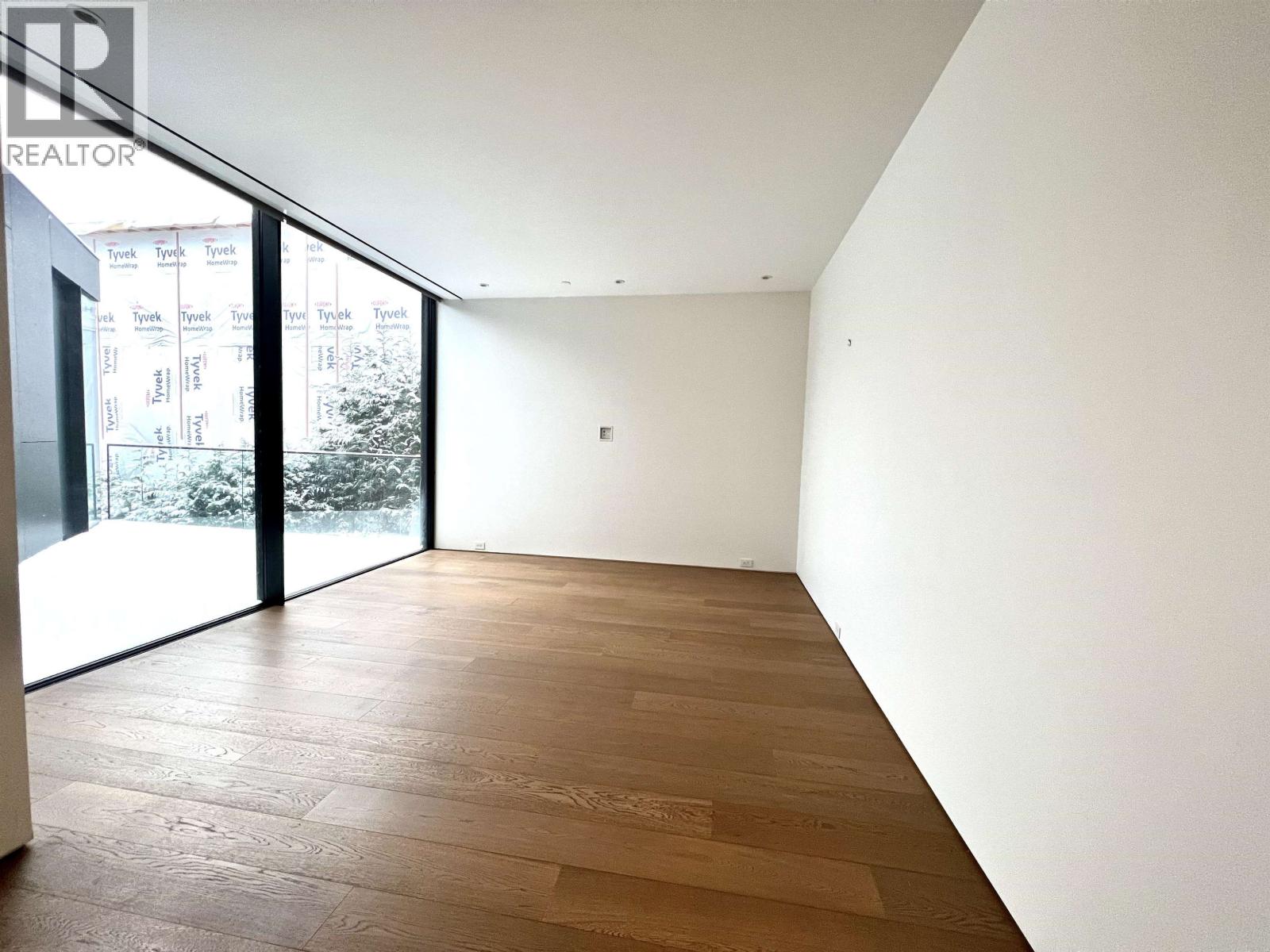 A room with wooden flooring and white walls.
