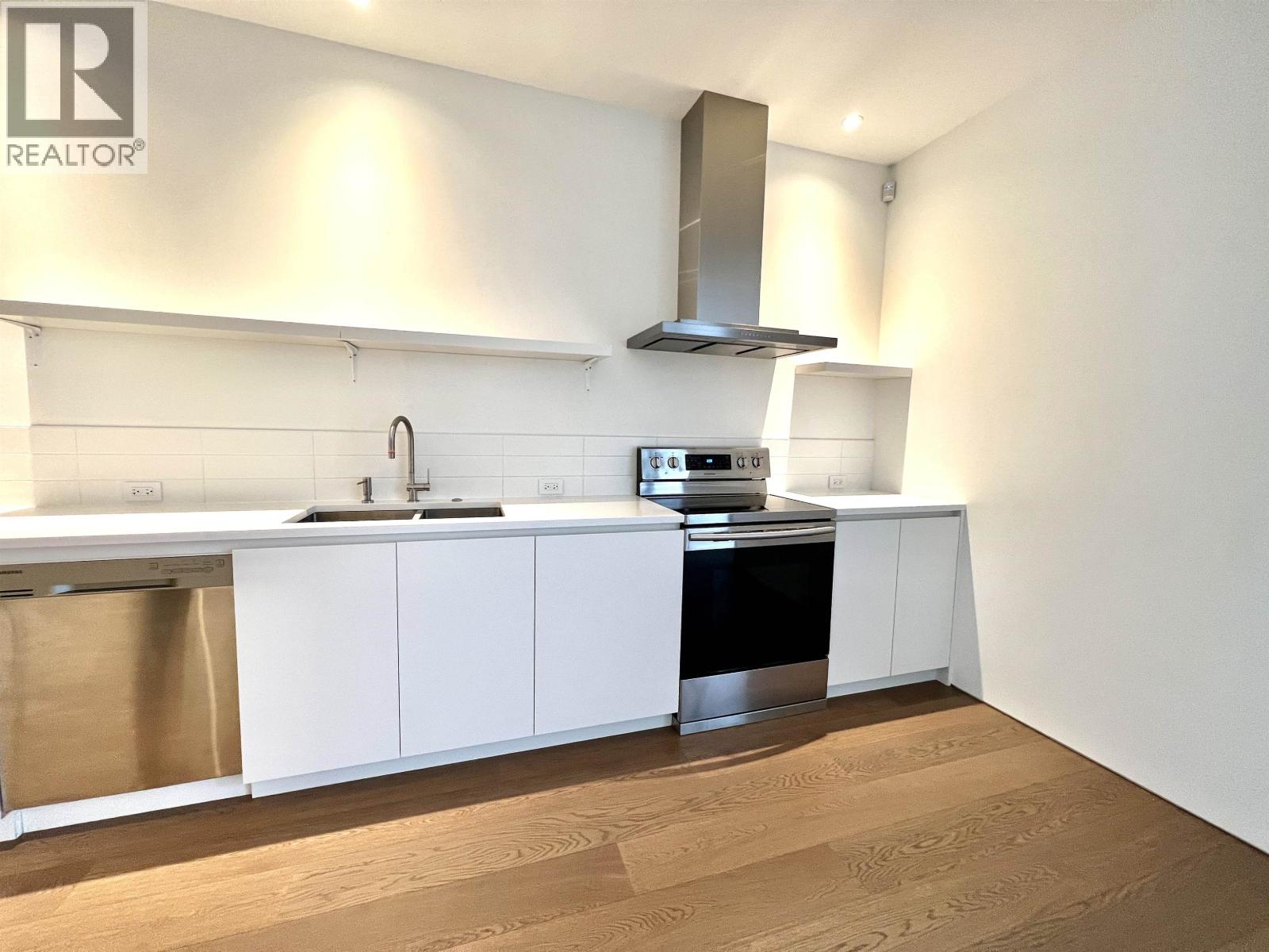 A modern kitchen with white cabinets and stainless steel appliances.
