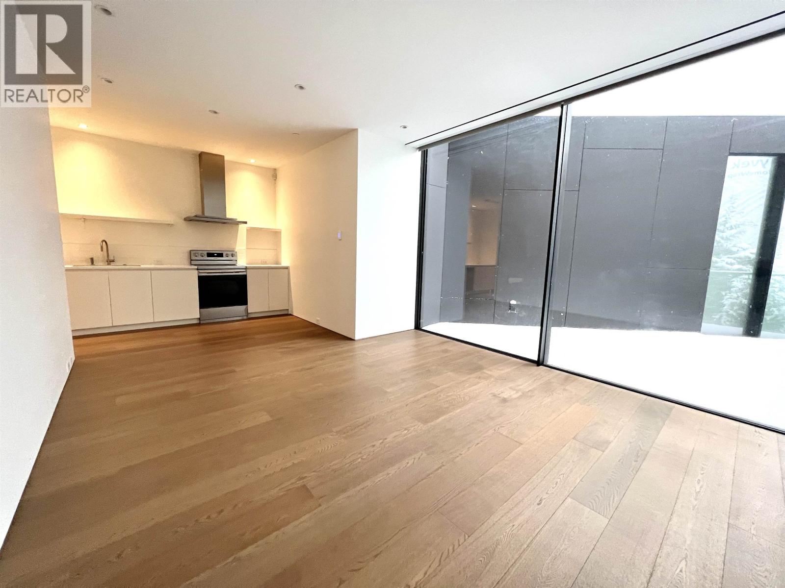 A modern kitchen with wooden floors and a stainless steel range hood.
