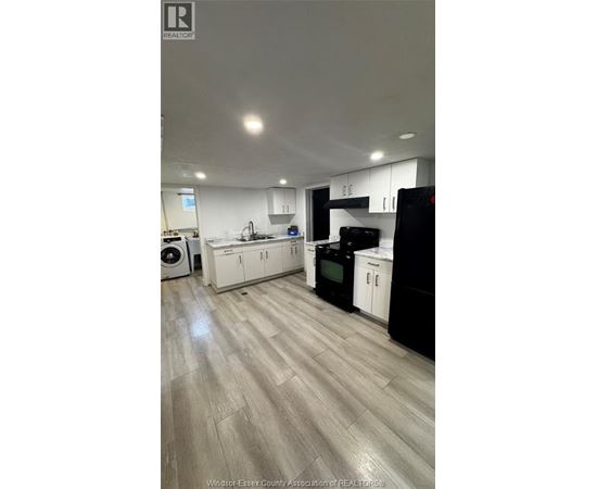A kitchen with black and white appliances and wooden floors.