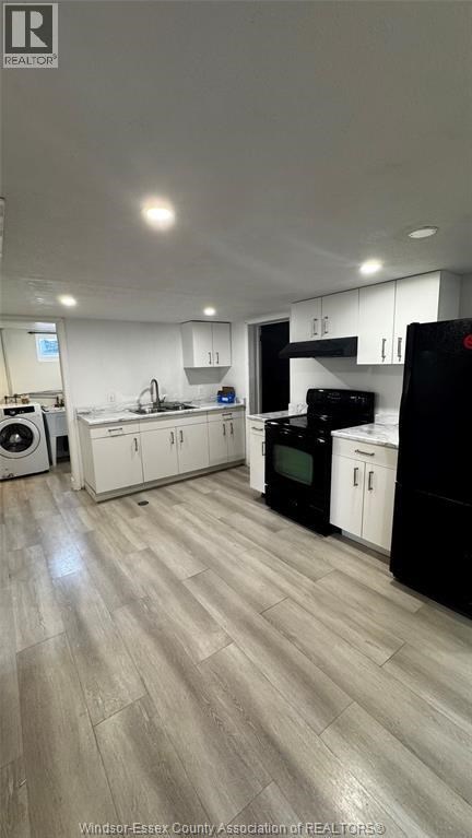 A kitchen with black and white appliances and wooden floors.