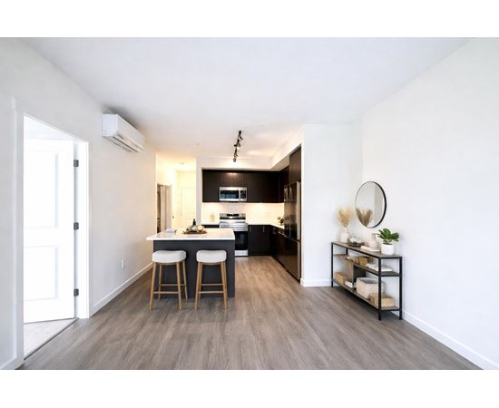 A modern kitchen with a bar stool and a small shelf with decorative items.