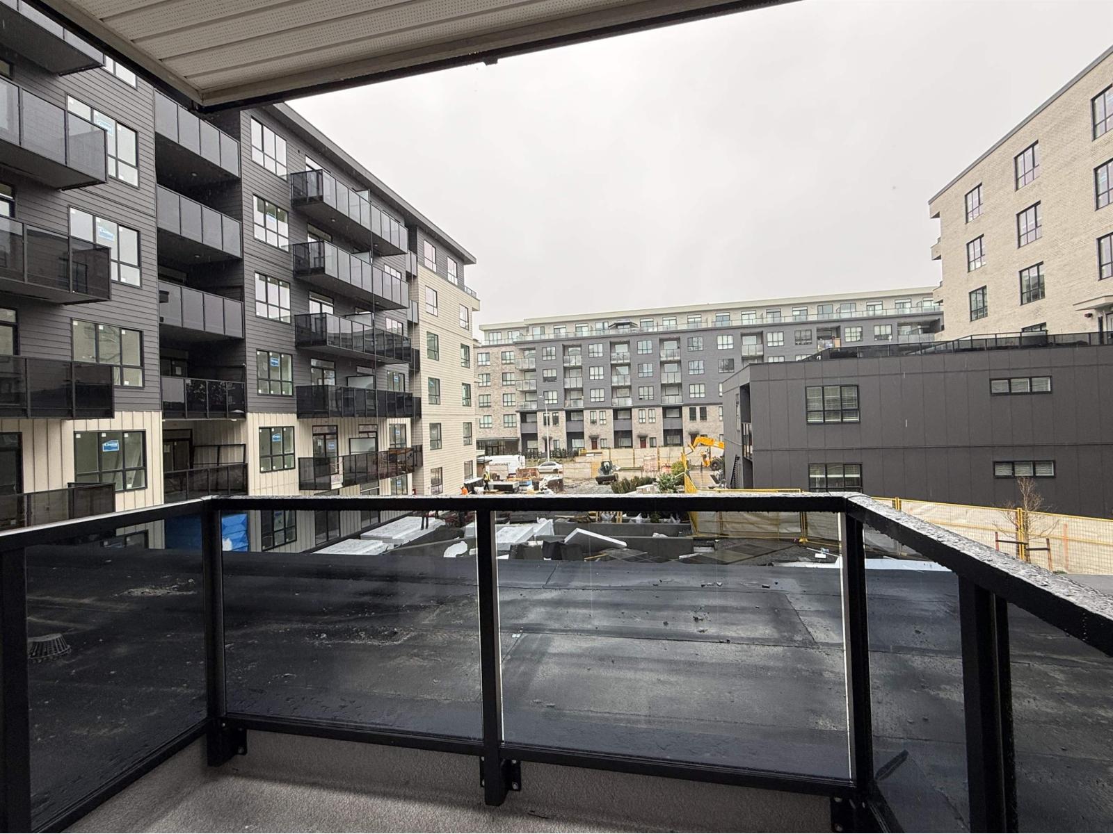 A balcony with a railing overlooks a parking lot and buildings.