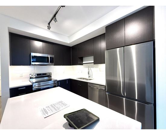 A modern kitchen with a white counter top and stainless steel appliances.