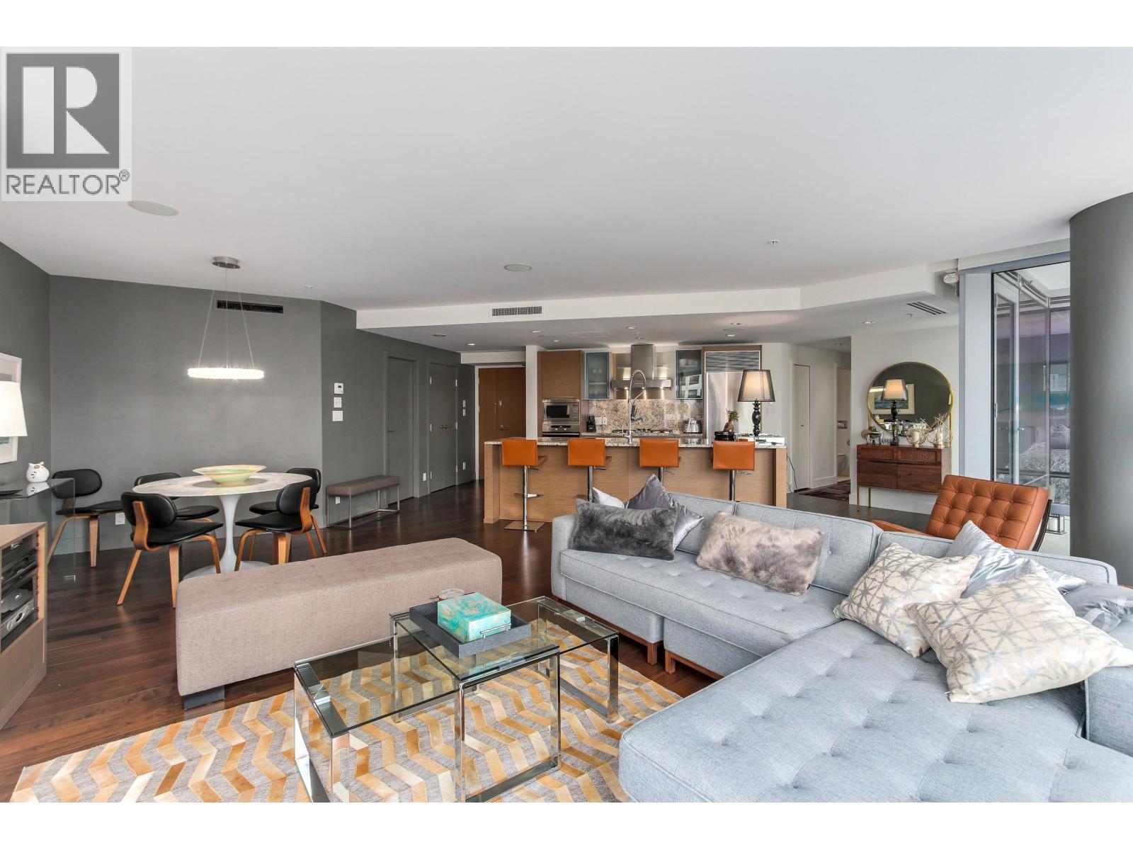 A living room with a grey couch and a glass coffee table.