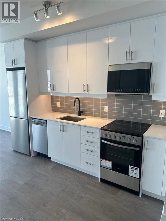 A kitchen with white cabinets and a black countertop.