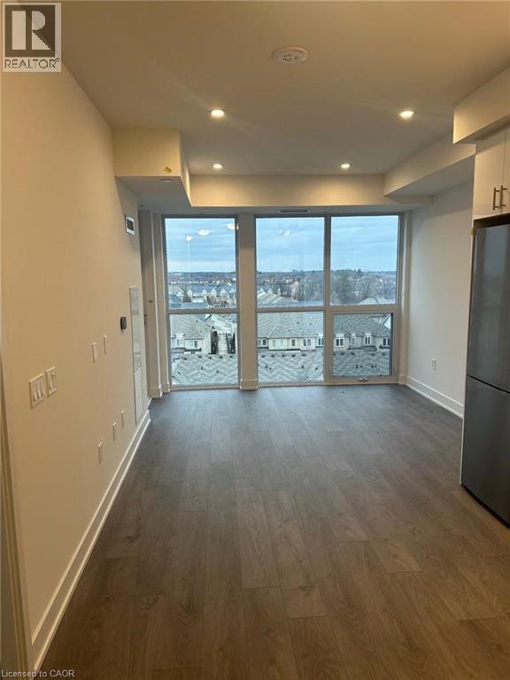 A spacious room with wooden flooring and a large window overlooking a snowy landscape.