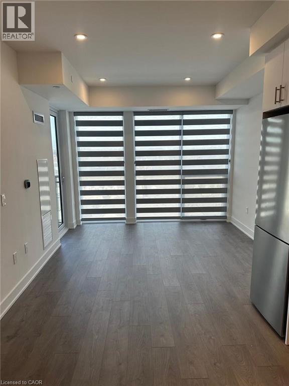 A modern kitchen with a stainless steel refrigerator and wooden flooring.