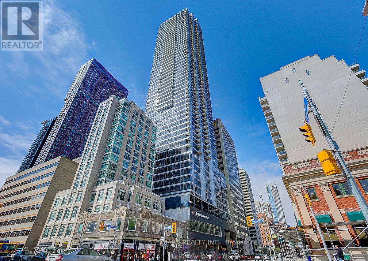A city street with a tall building in the background and a REALTOR® sign on the building.