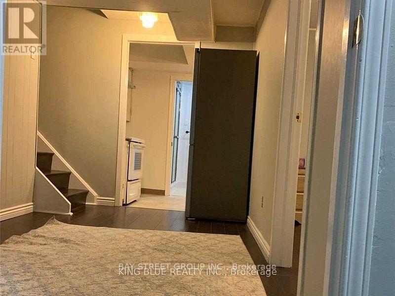A hallway with a refrigerator and stairs.