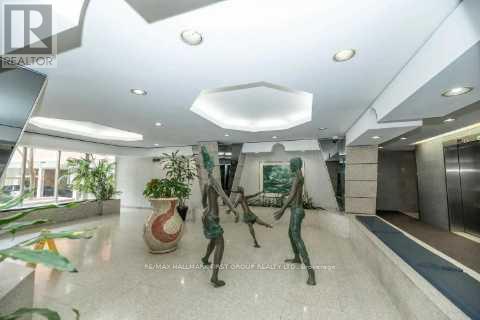 A spacious lobby with a statue, a plant, and a framed picture on the wall.