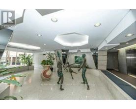 A spacious lobby with a statue, a plant, and a framed picture on the wall.