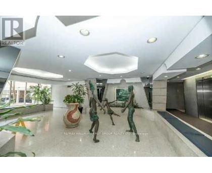 A spacious lobby with a statue, a plant, and a framed picture on the wall.
