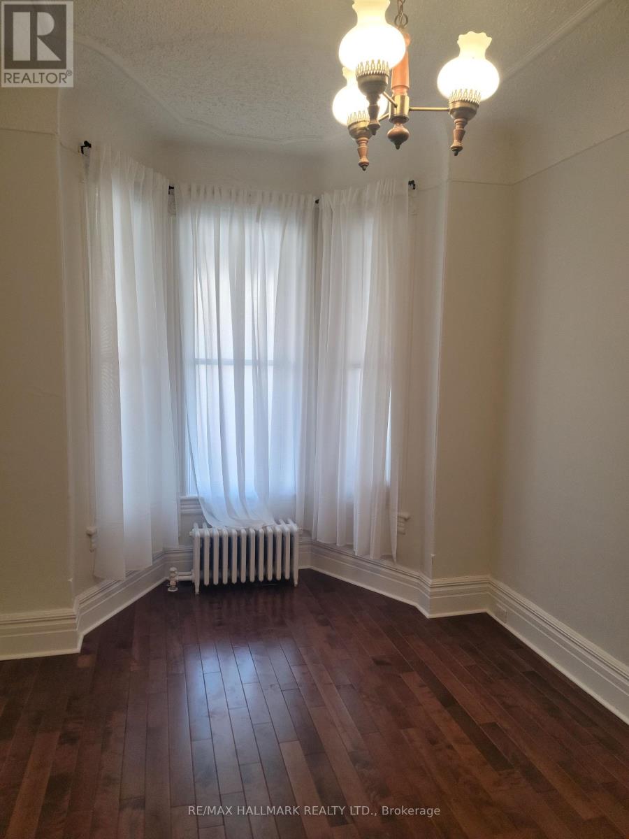 A room with a window covered by white curtains and a radiator beneath it.