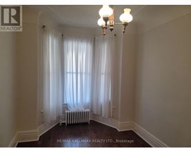 A room with a chandelier, a window with curtains, and a radiator.