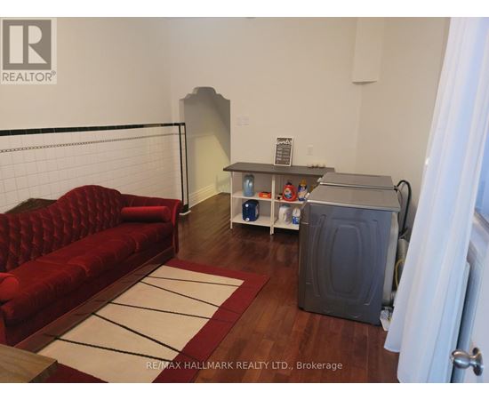 A living room with a red couch and a white rug.