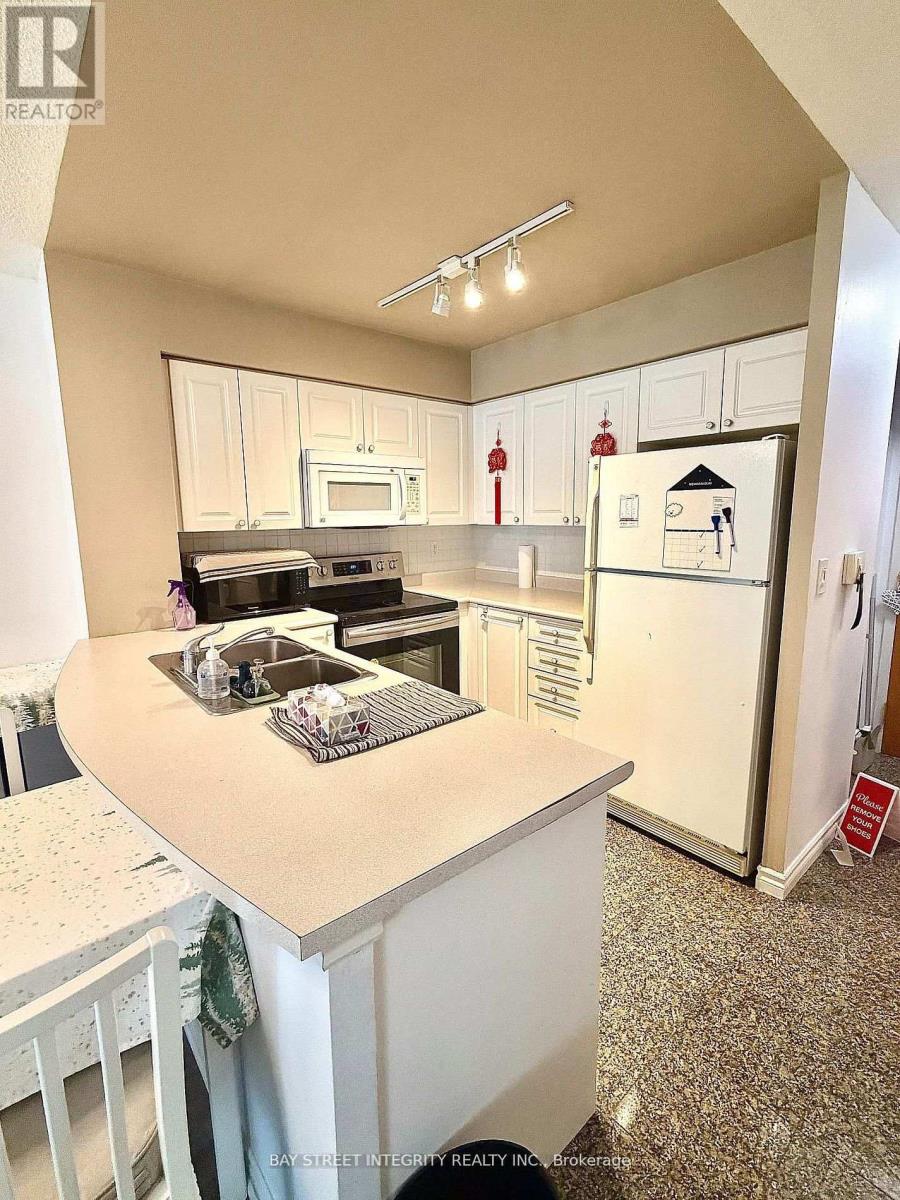 A kitchen with white cabinets and a refrigerator with a magnet on it.