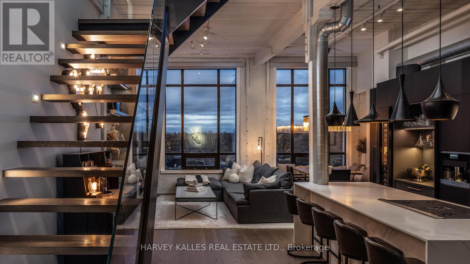 A modern living room with a staircase and a kitchen area.