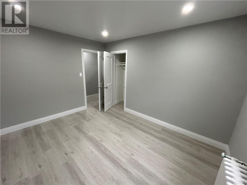 A room with a grey wall and a wooden floor with a white door.