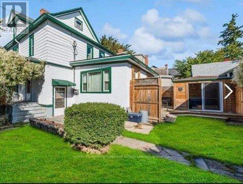 A white house with a green roof and a wooden fence.