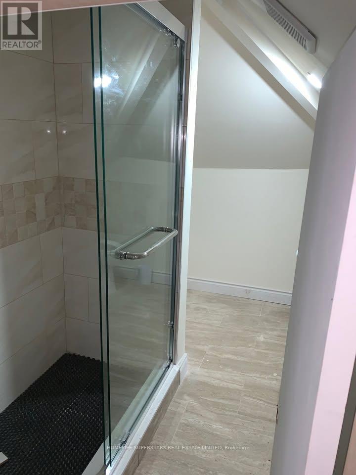 A shower area with a glass door and a black mat on the floor.