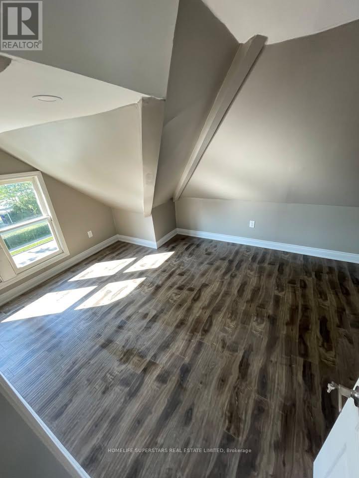A room with a wooden floor and a window letting in sunlight.
