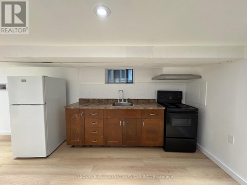 A kitchen with a white fridge, black oven, and wooden cabinets.