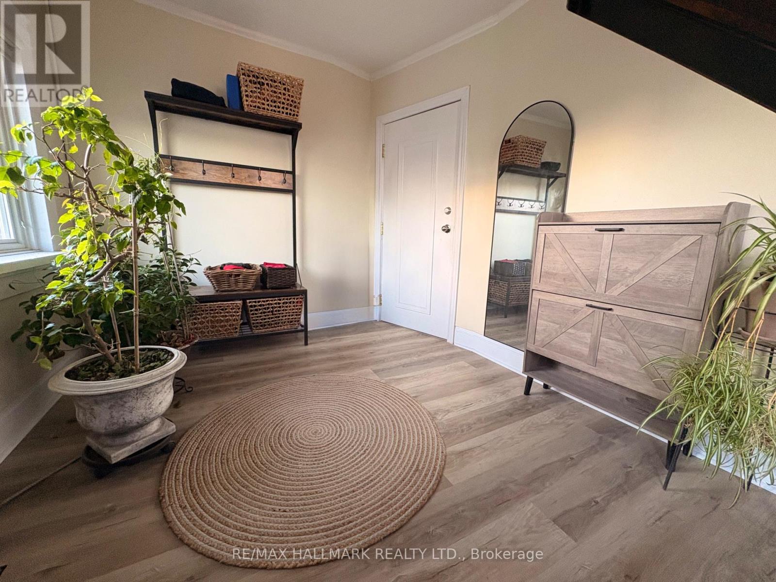 A room with a white door, a brown rug, and a wooden floor.