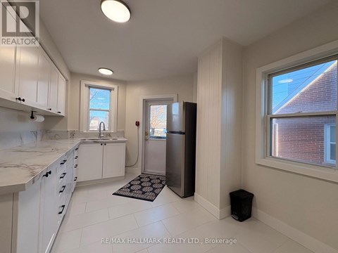 A kitchen with white cabinets and a black refrigerator.