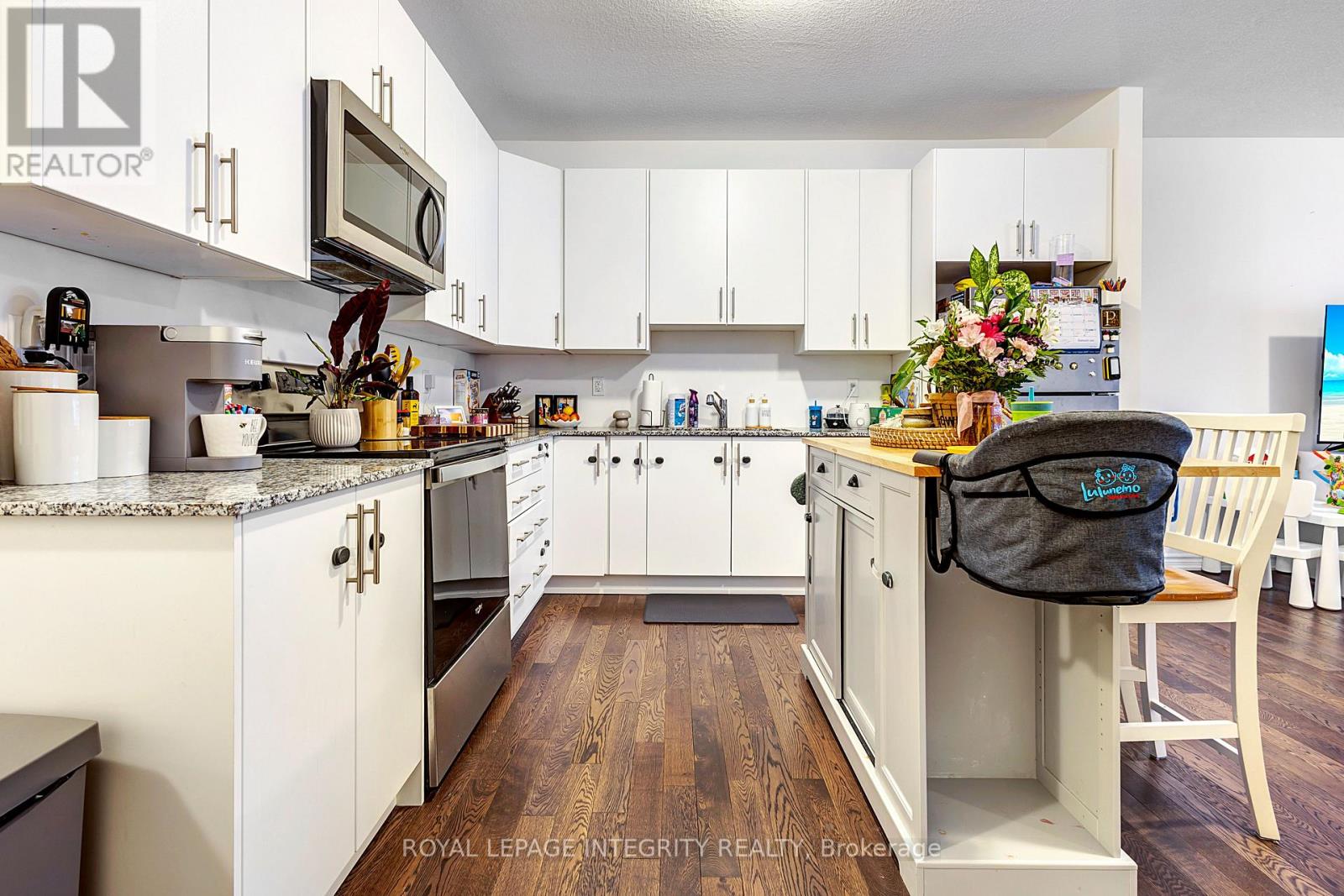A kitchen with white cabinets and a wooden floor.