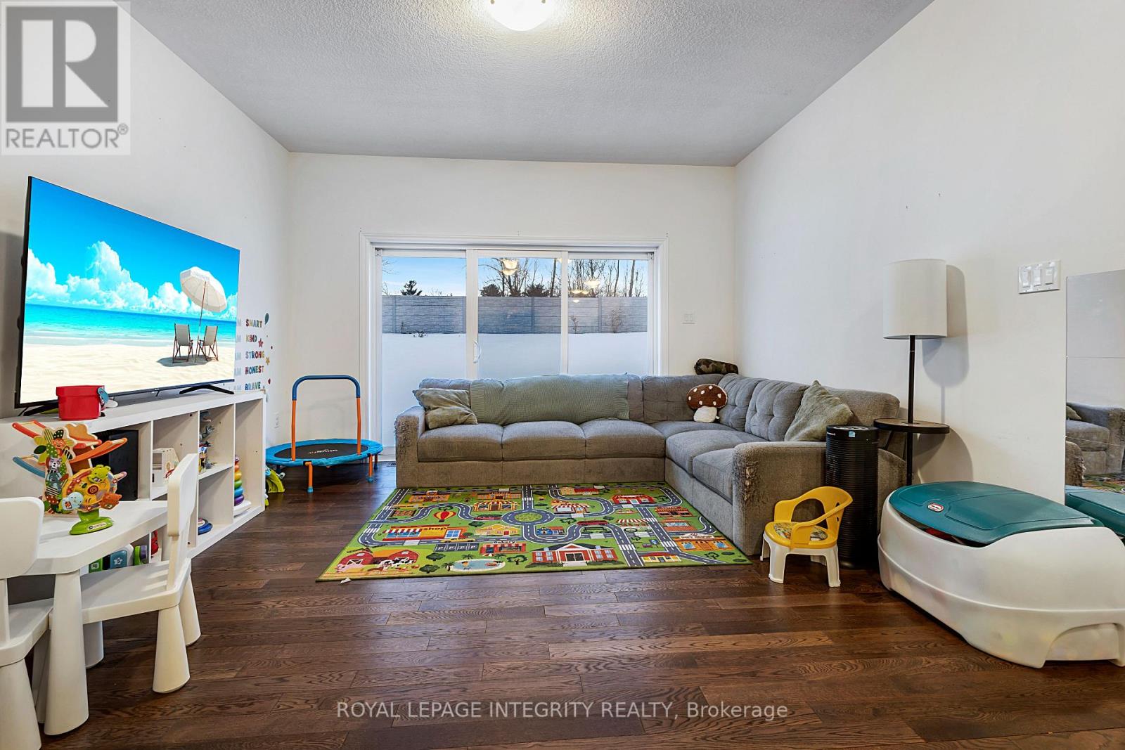 A living room with a grey couch and a television on the left side.